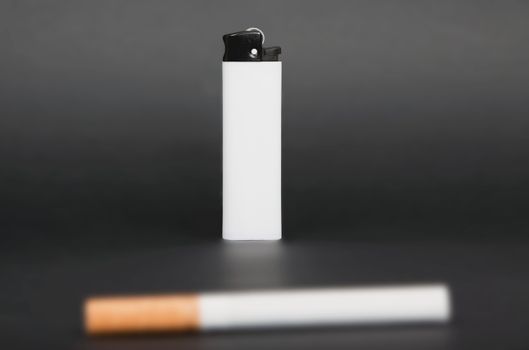 white lighter and one cigarette on gray background