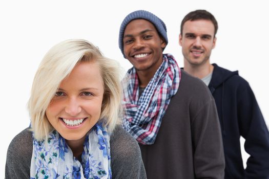 Three stylish friends looking at camera and smiling on white background