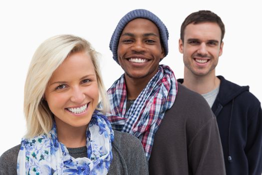 Three fashionable friends looking at camera and smiling on white background