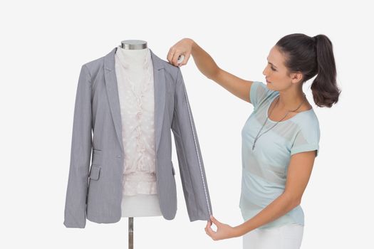 Fashion designer measuring blazer sleeve on white background