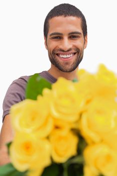 Handsome man offering bunch of yellow roses on white background