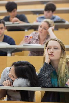 Students feeling bored in a lecture hall in college