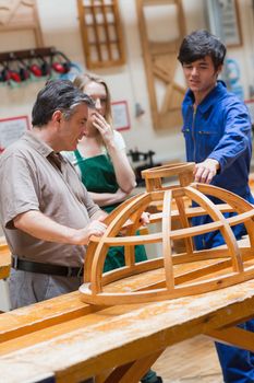 Students and a teacher standing in a woodwork class and talking about a structure