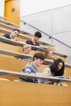 Students sitting in a lecture hall while learning and taking notes