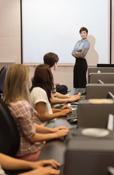 Teacher standing in front of projection screen in computer room in college