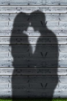 Shadows of couple embracing on wooden boards wall