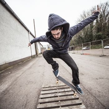 Skater doing ollie over wooden crate outside the skate park