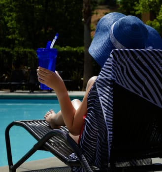 Girl in blue hat with water bottle by the pool