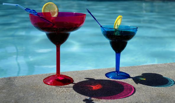 Two drinks in colour coctail glass by the swimming pool