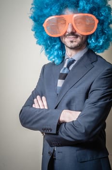 funny businessman with big orange glasses and blue wig on gray background