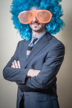 funny businessman with big orange glasses and blue wig on gray background