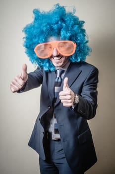 funny businessman with big orange glasses and blue wig on gray background