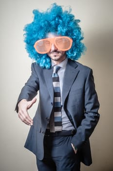 funny businessman with big orange glasses and blue wig on gray background