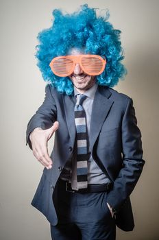 funny businessman with big orange glasses and blue wig on gray background