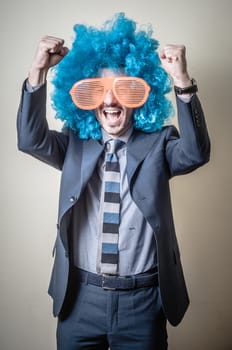 funny businessman with big orange glasses and blue wig on gray background