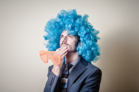 funny businessman with big orange glasses and blue wig on gray background