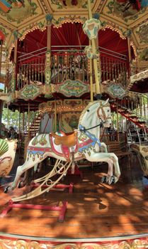 View of the inside of a colorful carousel with beautiful white horses