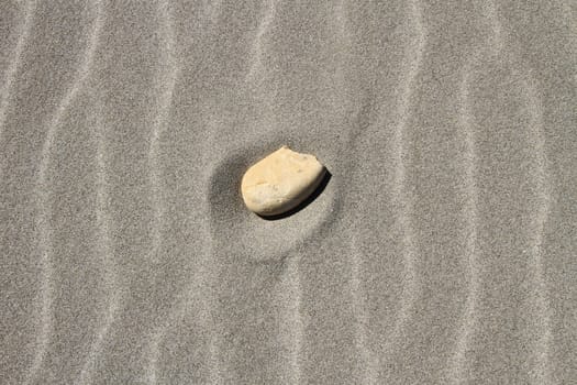 Stone alone in the middle of beach sand waves