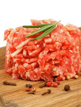 Fresh Raw Beef Burger with Rosemary and Pepper Corns on Wooden Cutting Board isolated on white background