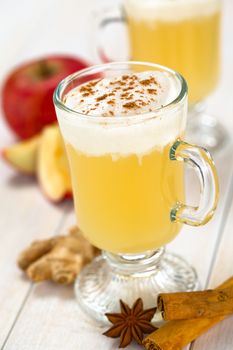 Homemade hot apple punch made of apple juice, ginger, anise and cinnamon with cinnamon whipped cream on top (Selective Focus, Focus on the front of the whipped cream)