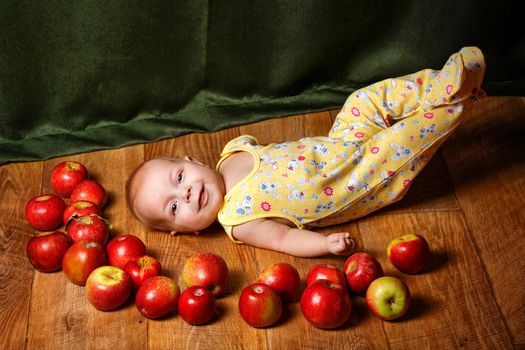 Redhead babe lying among ripe apple and smiling