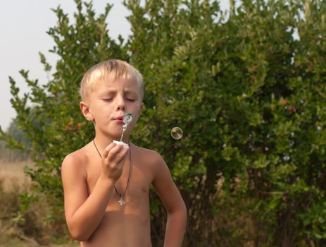 Boy blows bubbles in the garden on a summer day.