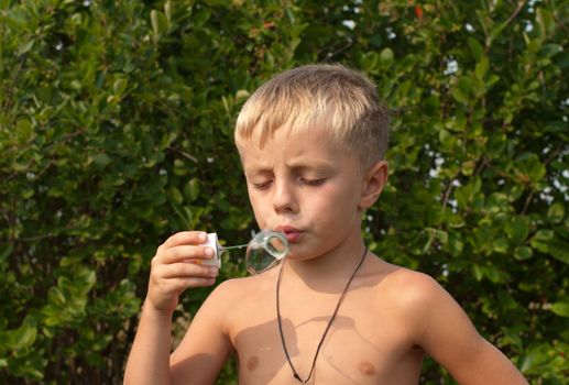 Boy blows bubbles in the garden on a summer day.