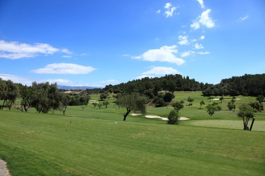 Panoramic view of a golf course with deserted manicured lush greens and fairways on a hot sunny summer day