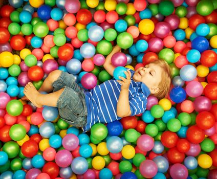 Happy child playing at colorful plastic balls playground high view