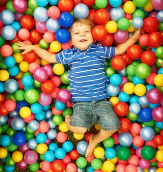 Happy child playing at colorful plastic balls playground high view