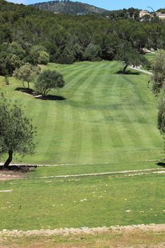 View down a neatly manicured fairway on a golf course showing the pattern of the lines left by the mower when the grass was cut