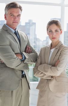 Business people standing with their arms crossed in a bright office