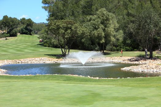 Water hazard on a golf course in the middle of the green or fairway with an ornamental fountain in the centre