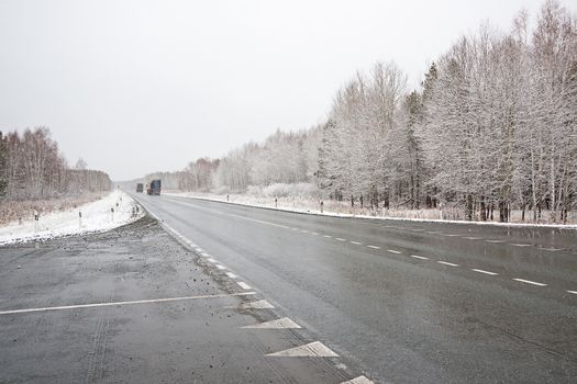 View of  trucks  on winter road against  cloudy sky.