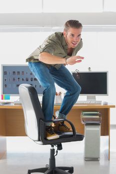 Handsome man surfing his office chair and having fun