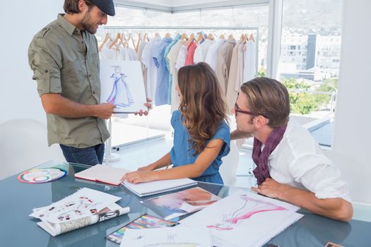 Fashion designer presenting his draw to colleagues during a meeting