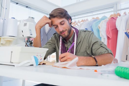 Smiling fashion designer working at his desk in a creative office