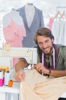 Fashion designer sewing and smiling to the camera