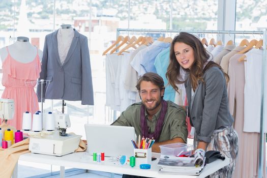 Two fashion designers in a creative office looking at camera