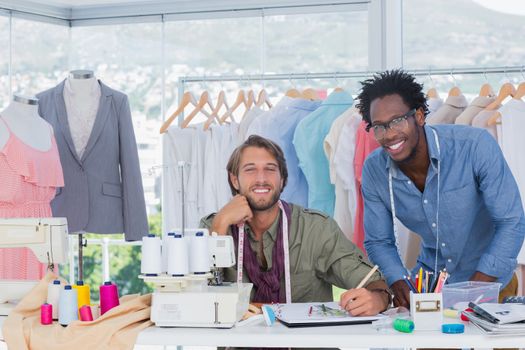 Fashion designers working together in a creative office and smiling to the camera