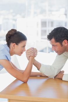 Competitive business people arm wrestling in the office