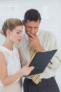 Serious business people looking at clipboard in office