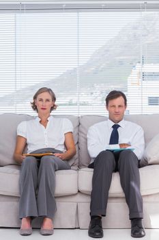 Stern business people sitting on couch in office