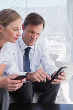 Smiling business people using mobile phones in office