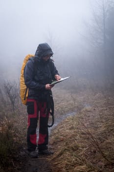 Young woman reading a map in the misty evening