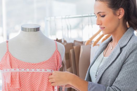 Fashion designer measuring dress on a mannequin