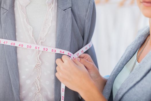 Fashion designer measuring blazer with measuring tape