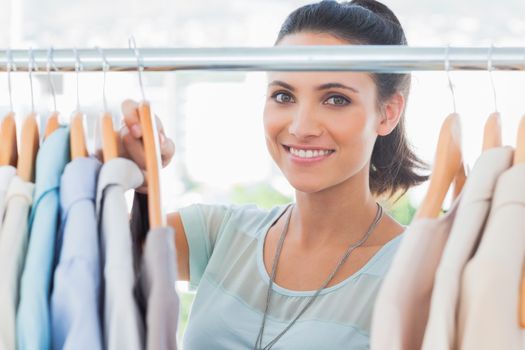 Smiling fashion designer looking at clothes in her studio