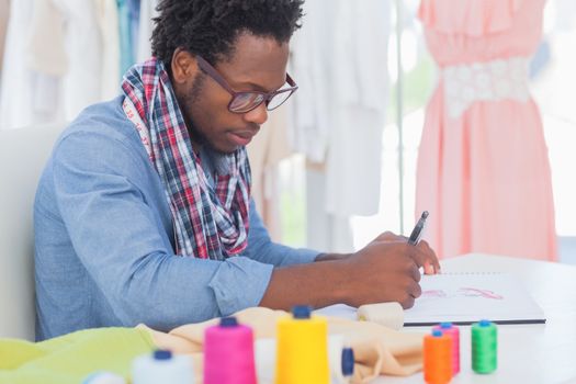 Fashion designer sitting at his desk drawing