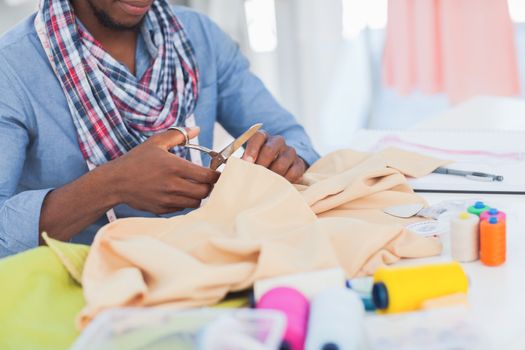 Fashion designer cutting textile in a creative office